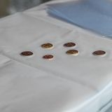 Sechs glänzende Münzen auf einer weißen Unterlage