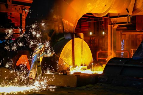 Ein Arbeiter steht in Schutzkleidung an einem Hochofen bei Thyssenkrupp