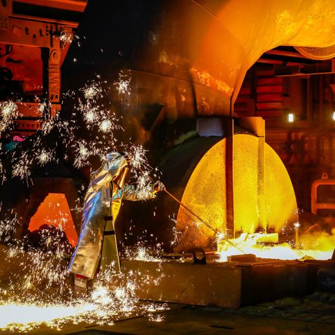Ein Arbeiter steht in Schutzkleidung an einem Hochofen bei Thyssenkrupp