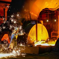 Ein Thyssenkrupp-Stahlarbeiter im Schutzanzug entnimmt eine 1500 Grad heiße Roheisenprobe