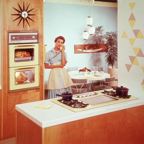 Tradwife: Eine Hausfrau aus den 50ern, steht in ihrer Küche, das Essen im Ofen und telefoniert