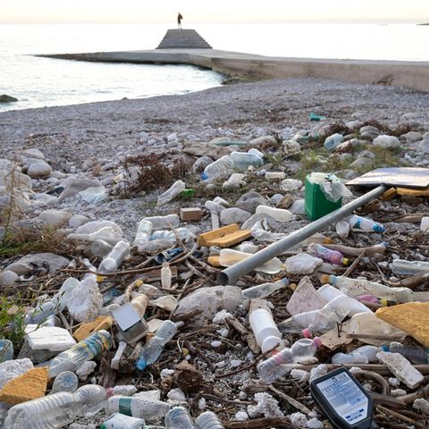 Plastik-Flaschen und anderer Müll liegen an einem Kiesstrand