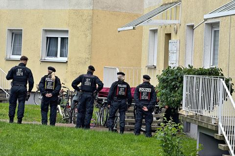 Fünf Polizistinnen und Polizisten stehen vor einem Haus