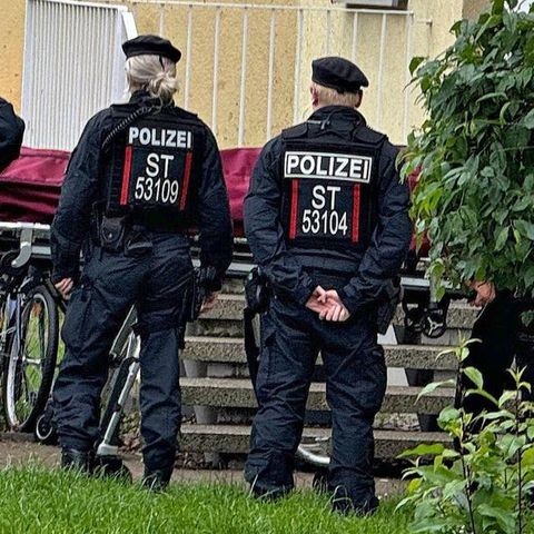 Fünf Polizistinnen und Polizisten stehen vor einem Haus