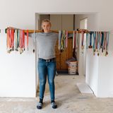 Spitzensport Frau mit Ruder auf den Schultern an dem viele Medaillen hängen