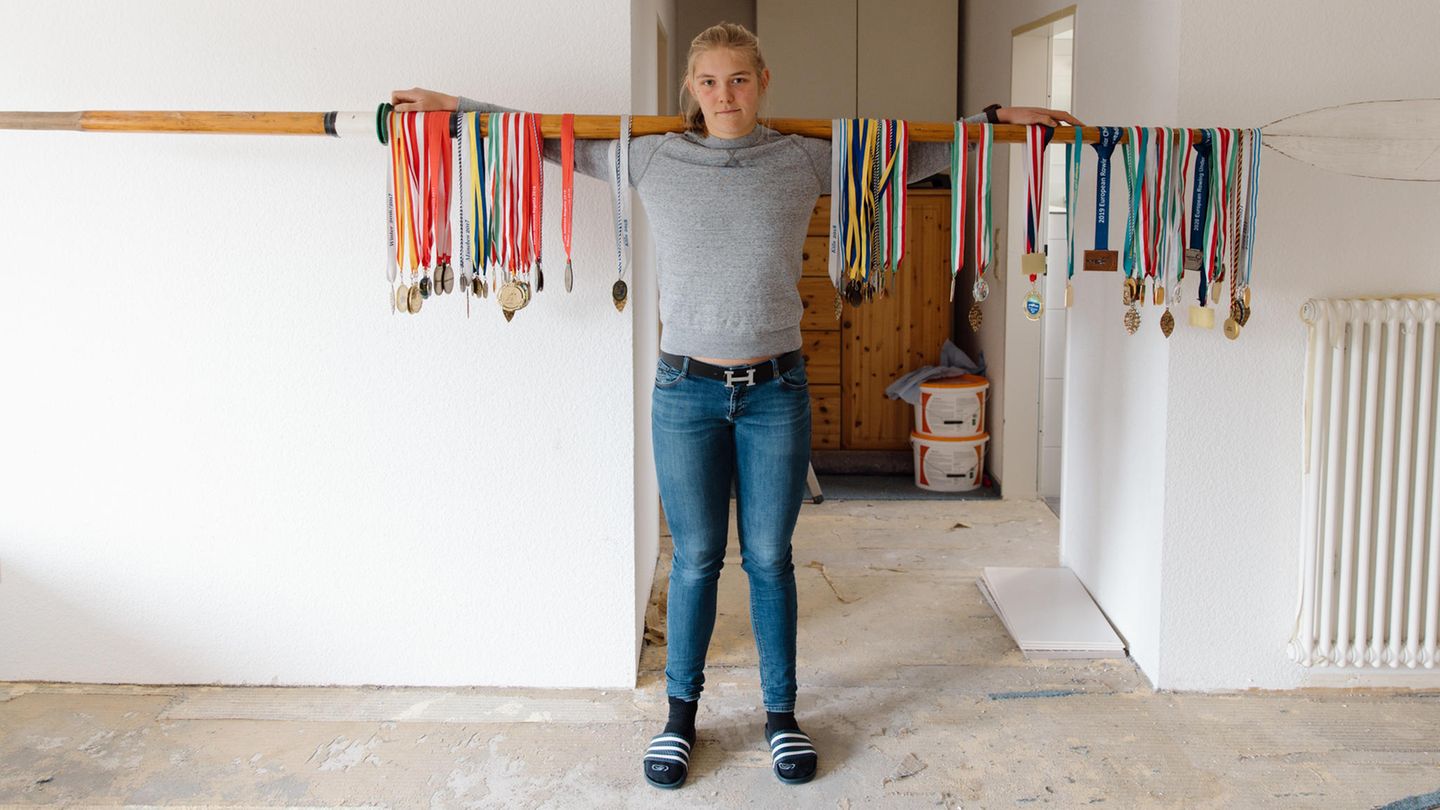 Spitzensport Frau mit Ruder auf den Schultern an dem viele Medaillen hängen