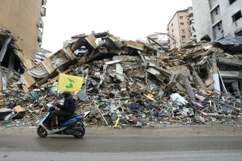Hisbollah-Anhänger vor zerstörtem Gebäude in Südbeirut