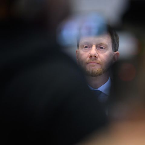 Halb verborgen durch eine Unschärfe im Vordergrund sieht man Michael Kretschmers Gesicht