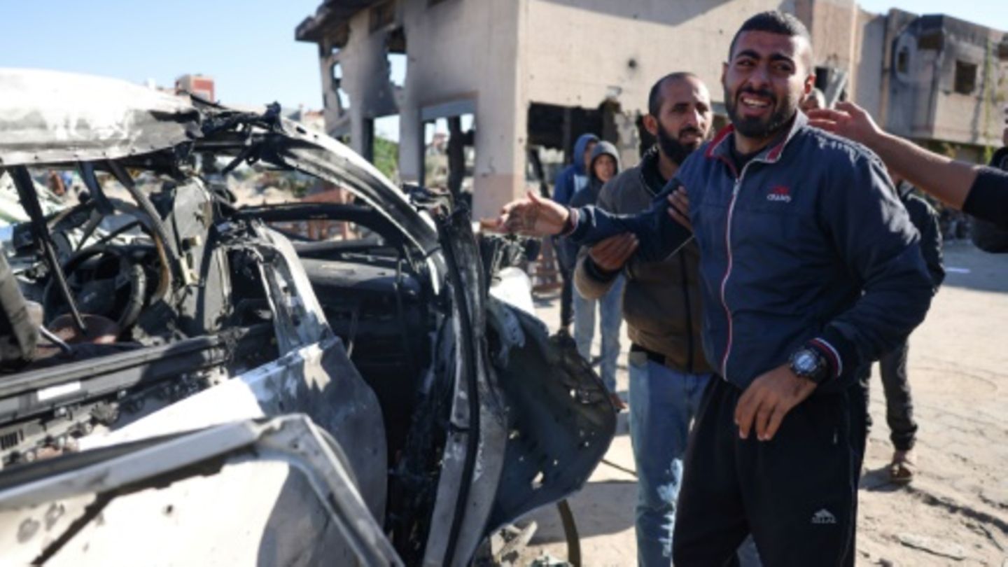 Menschen vor bei israelischem Angriff getroffenem Auto in Chan Junis