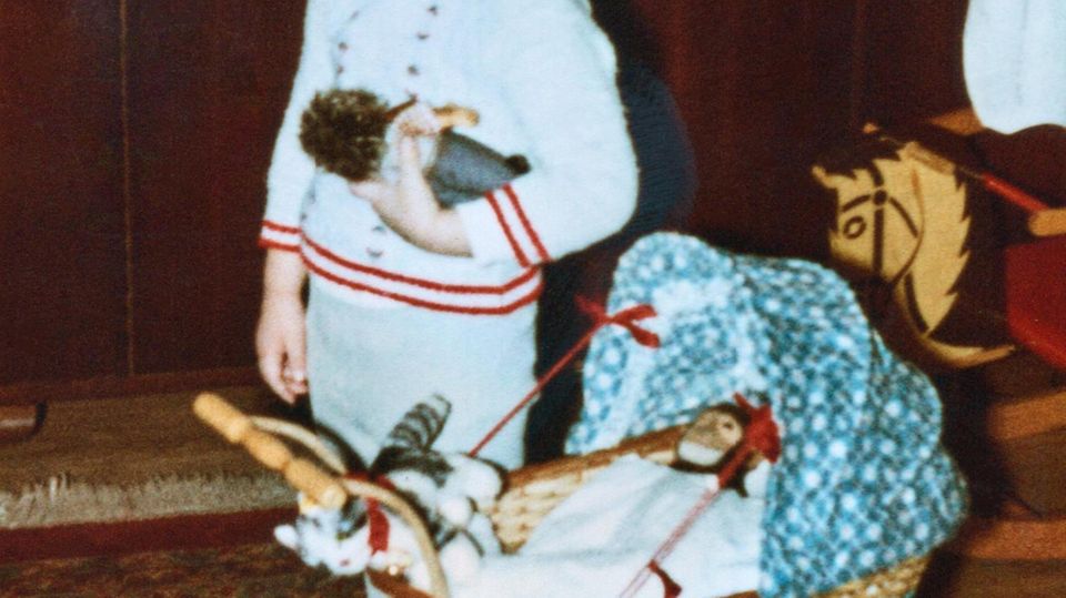 Little boy with doll stroller and stuffed toys in front of Christmas tree photographed Christmas  1970