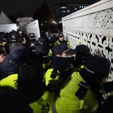 Daraufhin versuchen Menschen in die Nationalversammlung in Seoul zu gelangen, während Polizisten Wache stehen