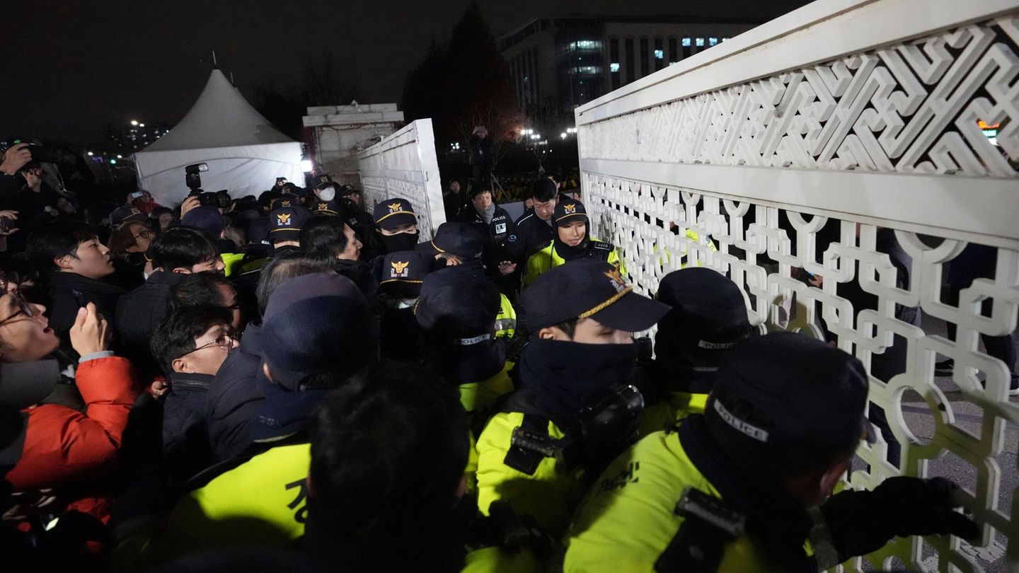 Daraufhin versuchen Menschen in die Nationalversammlung in Seoul zu gelangen, während Polizisten Wache stehen