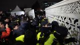 Daraufhin versuchen Menschen in die Nationalversammlung in Seoul zu gelangen, während Polizisten Wache stehen