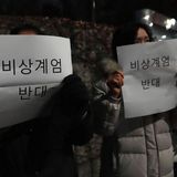 Menschen tragen Schilder mit der Aufschrift "Gegen das Kriegsrecht" vor der Nationalversammlung in Seoul