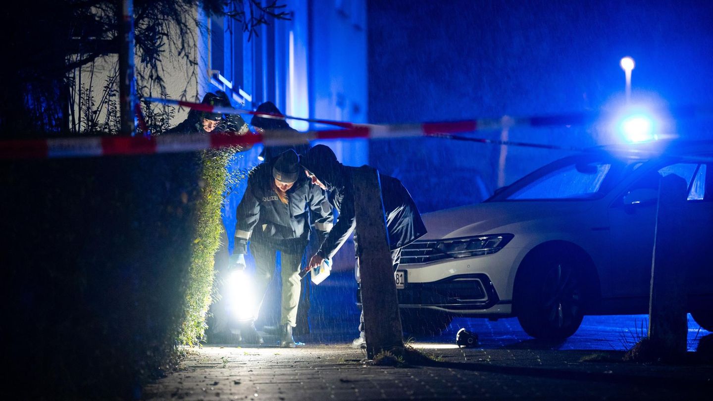 Neben einem Auto mit Blaulicht suchen zwei Polizisten mit Taschenlampen den Boden in Kiel ab