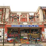 Die Rote Flora in Hamburg mit einem Schild "Achidi-John-Platz"