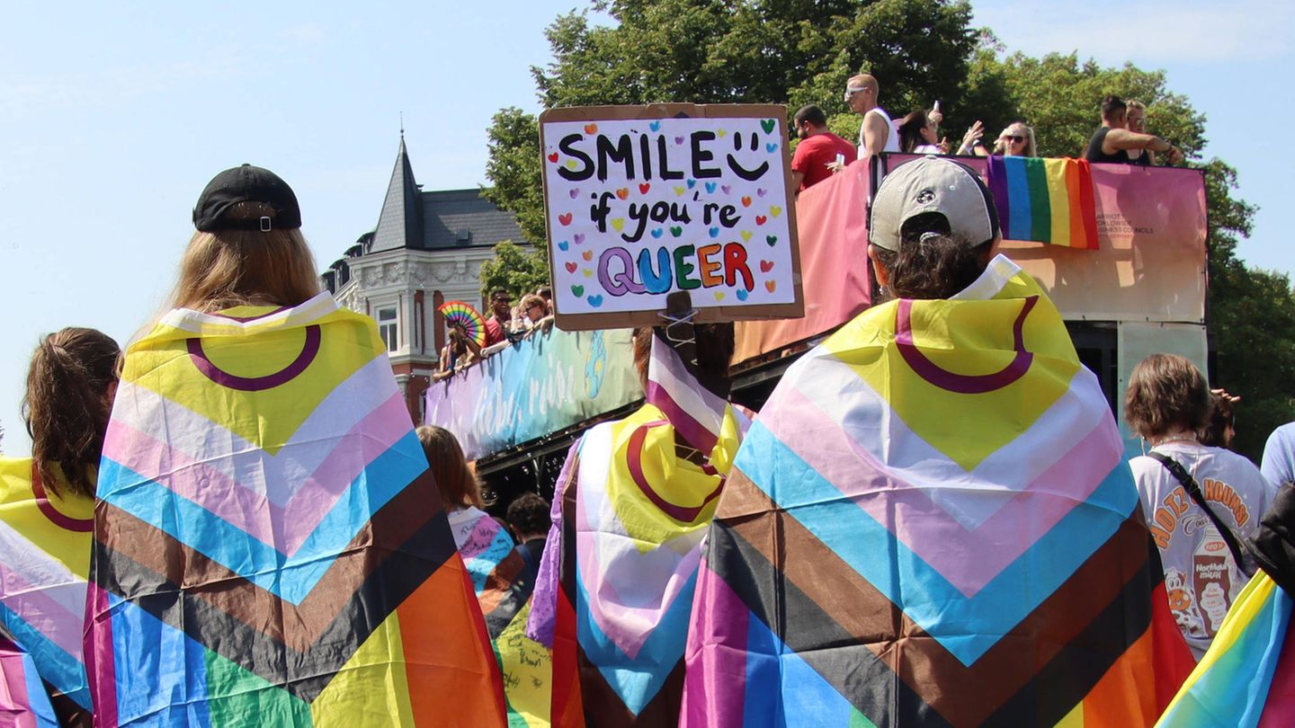 Menschen mit Regenbogenflagge feiern den Christopher-Street-Day in Hamburg