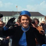 Hape kerkeling winkt im blauen Kostüm und mit Hut als Königin Beatrix vor Schloss Bellevue