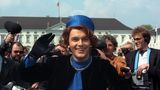 Hape kerkeling winkt im blauen Kostüm und mit Hut als Königin Beatrix vor Schloss Bellevue