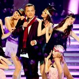 Kerkeling mit Schal und Mikro auf der Bühne, umrahmt von einem Show-Ballett