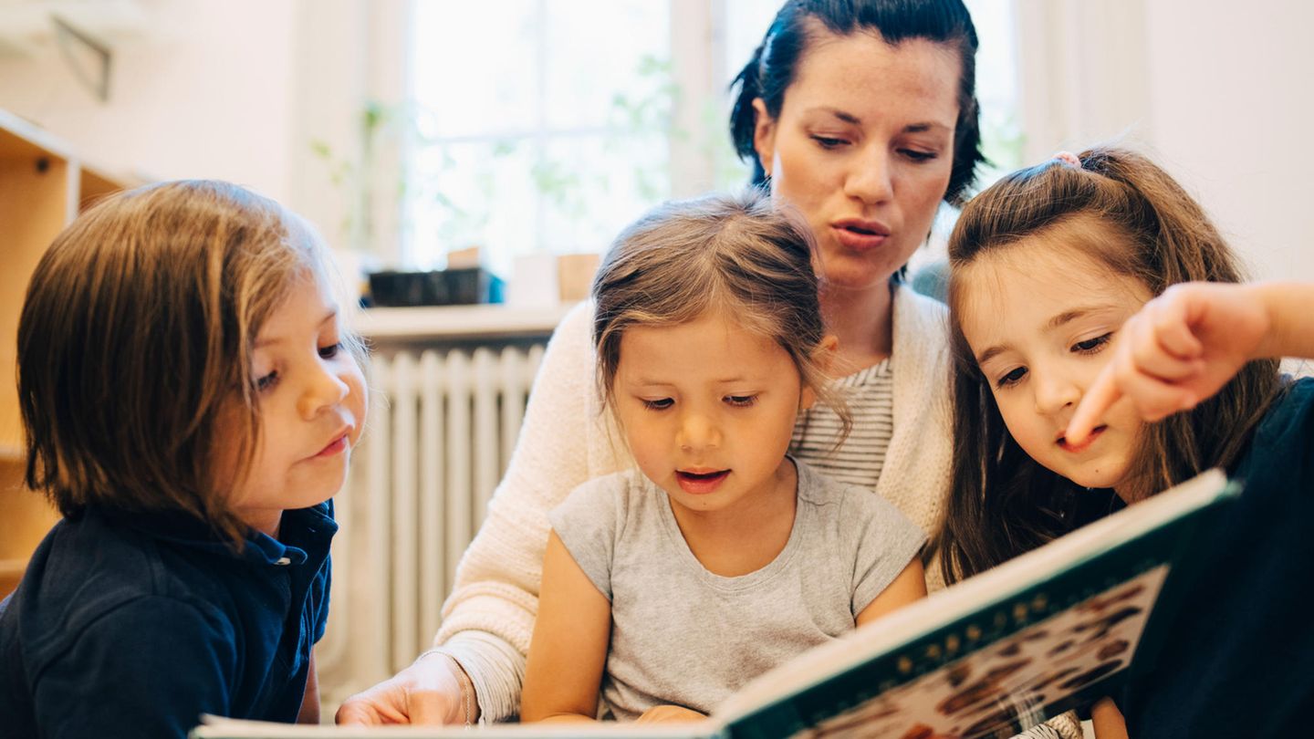 Symbolbild Kita-Streit: Eine Erzieherin liest Kindern aus einem Buch vor