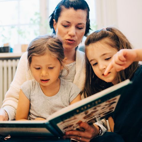 Symbolbild Kita-Streit: Eine Erzieherin liest Kindern aus einem Buch vor
