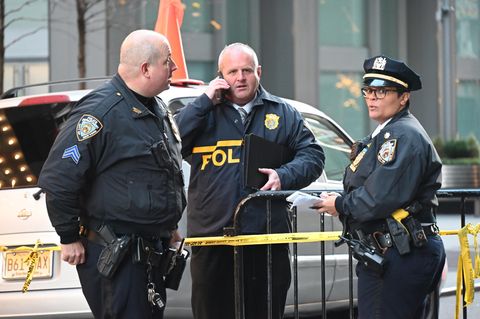 Nach dem Attentat auf Brian Thompson in New York stehen Polizisten an einer Absperrung zum Tatort