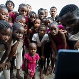 Die Kinder haben sich in der Tanzschule um einen Handybildschirm versammelt.