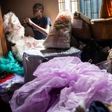 Eine Tanzschülerin näht an einem Kostüm, umgeben von buntem Tüll