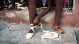 Eine Ballettschülerin bindet einen Spitzenschuh an ihrem rechten Fuß