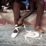 Eine Ballettschülerin bindet einen Spitzenschuh an ihrem rechten Fuß