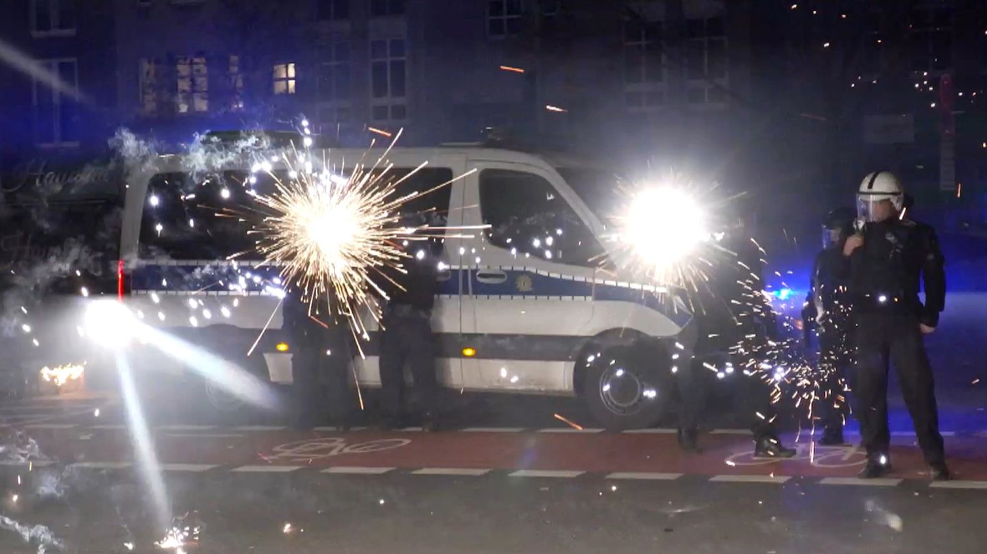 Polizeibeamte stehen in der Silvesternacht hinter explodierendem Feuerwerk (Symbolbild Pyrotechnik)
