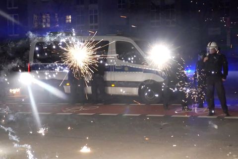 Polizeibeamte stehen in der Silvesternacht hinter explodierendem Feuerwerk (Symbolbild Pyrotechnik)