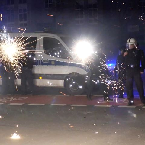 Polizeibeamte stehen in der Silvesternacht hinter explodierendem Feuerwerk (Symbolbild Pyrotechnik)