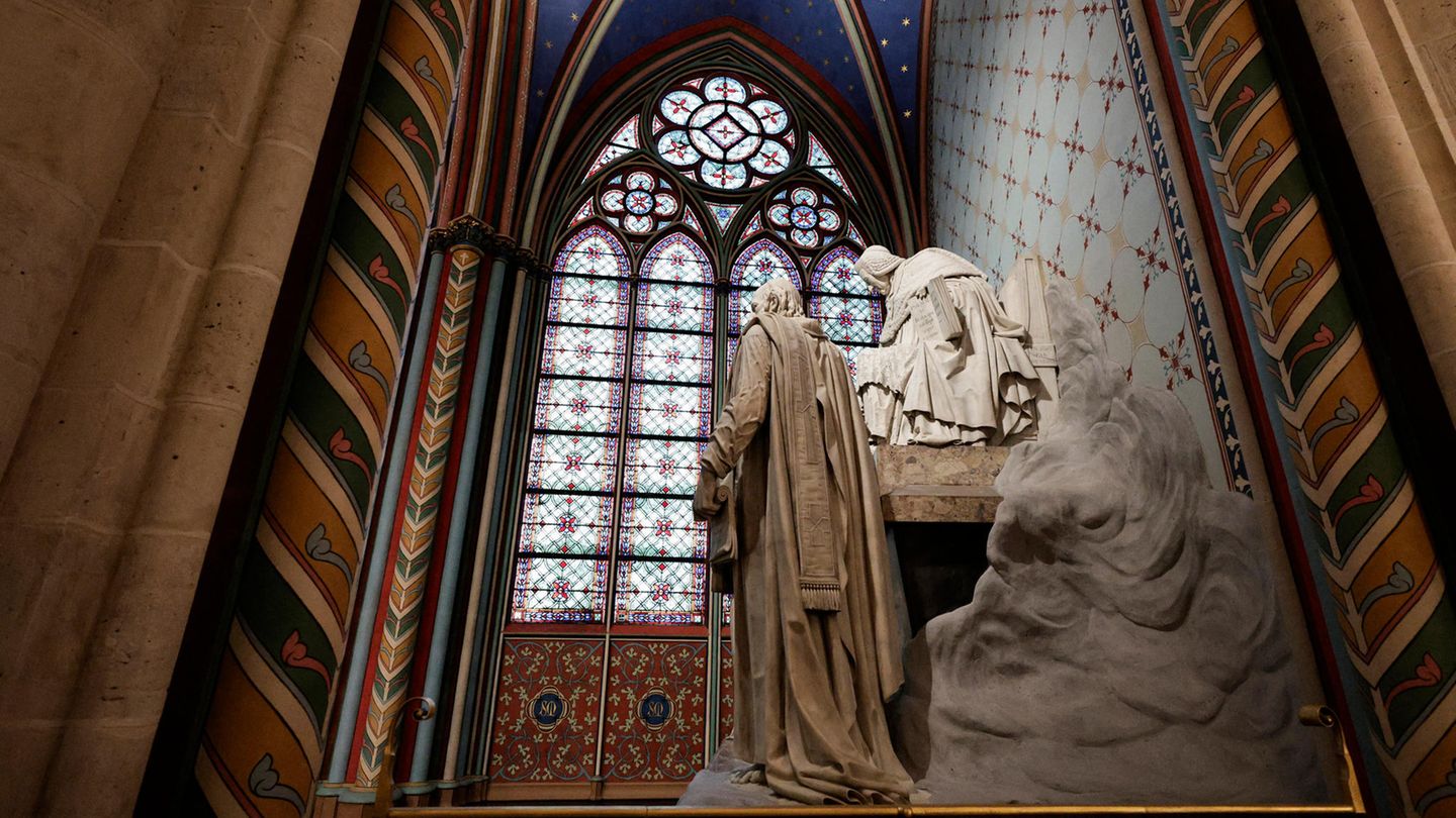Die steinerne Statue eines Mannes steht vor einem Buntglasfenster der Kathedrale