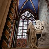 Die steinerne Statue eines Mannes steht vor einem Buntglasfenster der Kathedrale