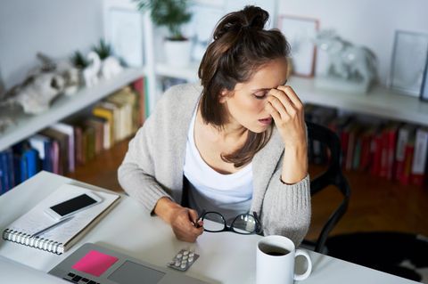 Burnout: Verzweifelte, überarbeitete Frau am Schreibtisch