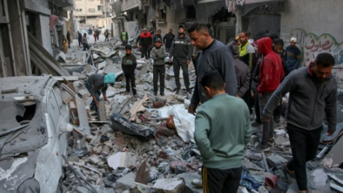 Menschen vor zerstörten Häusern in der Stadt Gaza