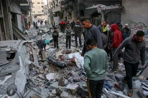 Menschen vor zerstörten Häusern in der Stadt Gaza