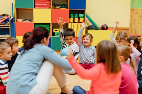 Kinder sitzen in der Kita im Kreis um ihre Erzieherin