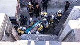 Rettungshelfer tragen eine verletzte Person aus einem Haus