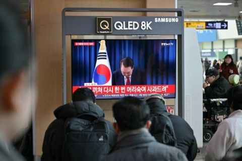 Passagiere sehen Yoons Ansprache in einem Bahnhof in Seoul