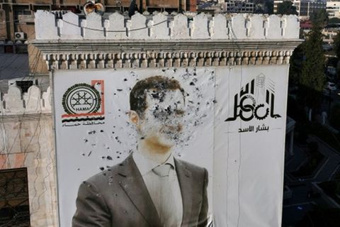 Von Kugeln zerlöchertes Assad-Porträt am Rathaus von Hama