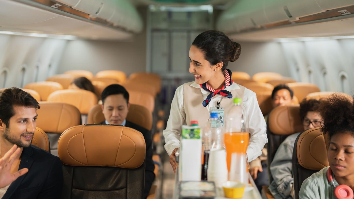 Eine Stewardess bietet auf einer Flug-Reise einem Passagier Getränke an