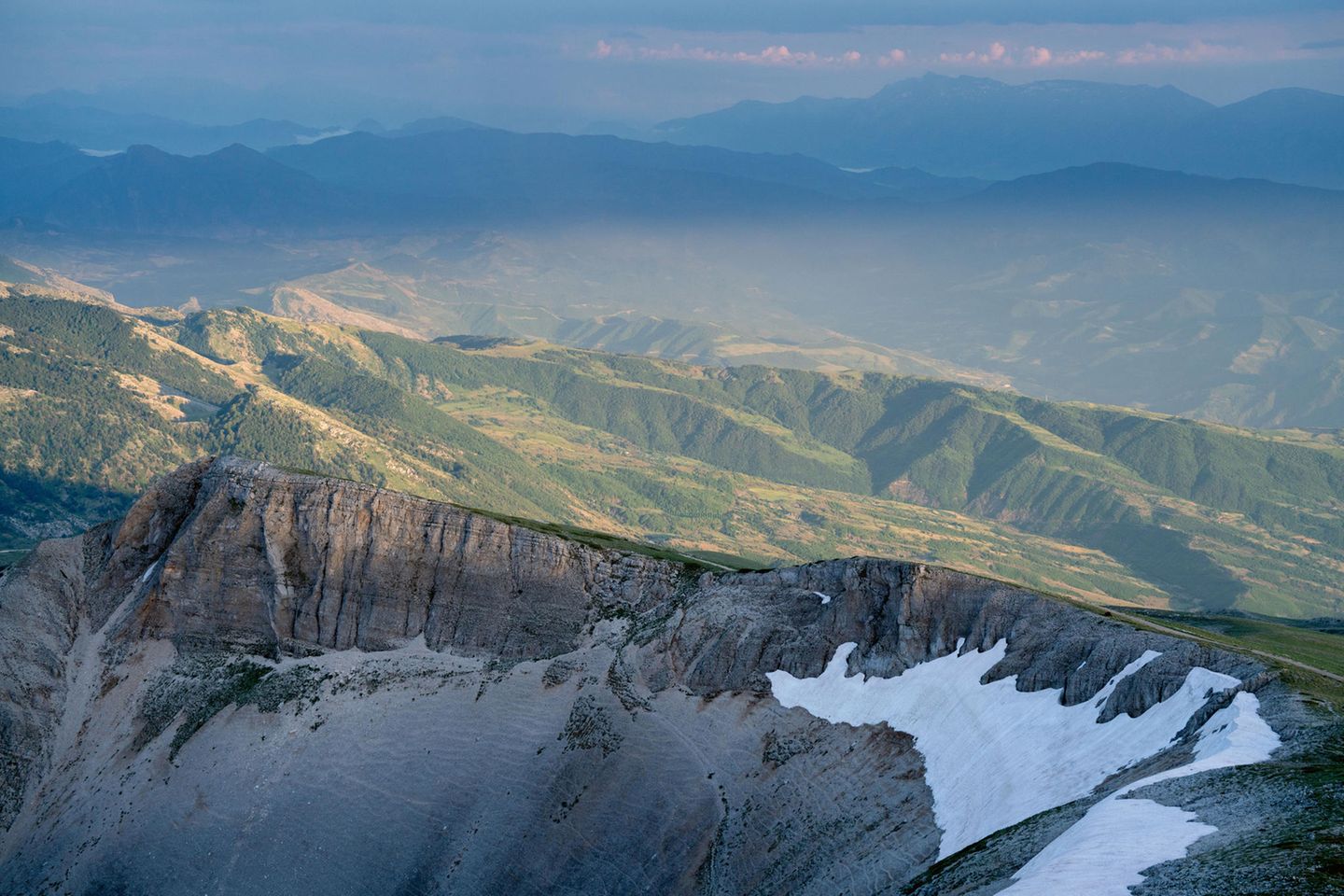 Europas heilige Berge: Steilwand mit grünen Bergketten im Hintergrund