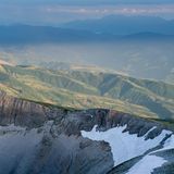Europas heilige Berge: Steilwand mit grünen Bergketten im Hintergrund
