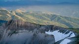 Europas heilige Berge: Steilwand mit grünen Bergketten im Hintergrund