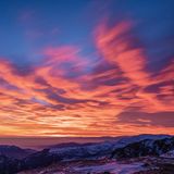 Europas heilige Berge: Schneebedeckte Gipfel mit feuerrotem Sonnenuntergang