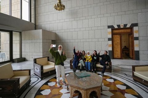 Eine Gruppe von Menschen macht ein Familienfoto, während sie auf einer Couch in einem Saal des Präsidentenpalastes sitzen
