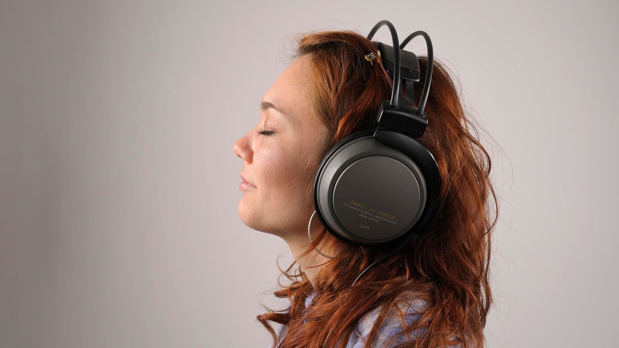 Junge Frau mit roten Haaren mit Kopfhörern